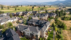 Una zona residencial con varias casas, un campo de golf y montañas al fondo.