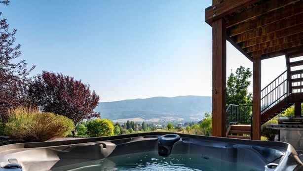 Un jacuzzi con vistas a montañas y una terraza de madera.