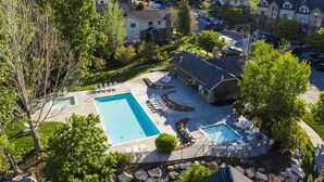 Una zona residencial con dos piscinas, un club social y un campo de golf al fondo.