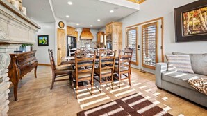 Un comedor amplio con una mesa y sillas de madera, una cocina con armarios de madera, y una sala de estar con un sofá y un cuadro.