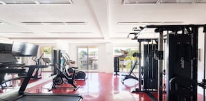 Academia com esteiras, equipamentos elípticos e aparelhos de musculação.