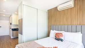 Habitación de hotel con cama, armario, kitchenette y aire acondicionado.