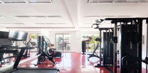 Un gimnasio con cintas de correr, elípticas y equipos de levantamiento de pesas.