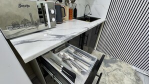 A kitchen with a marble countertop, a coffee maker, and a sink.