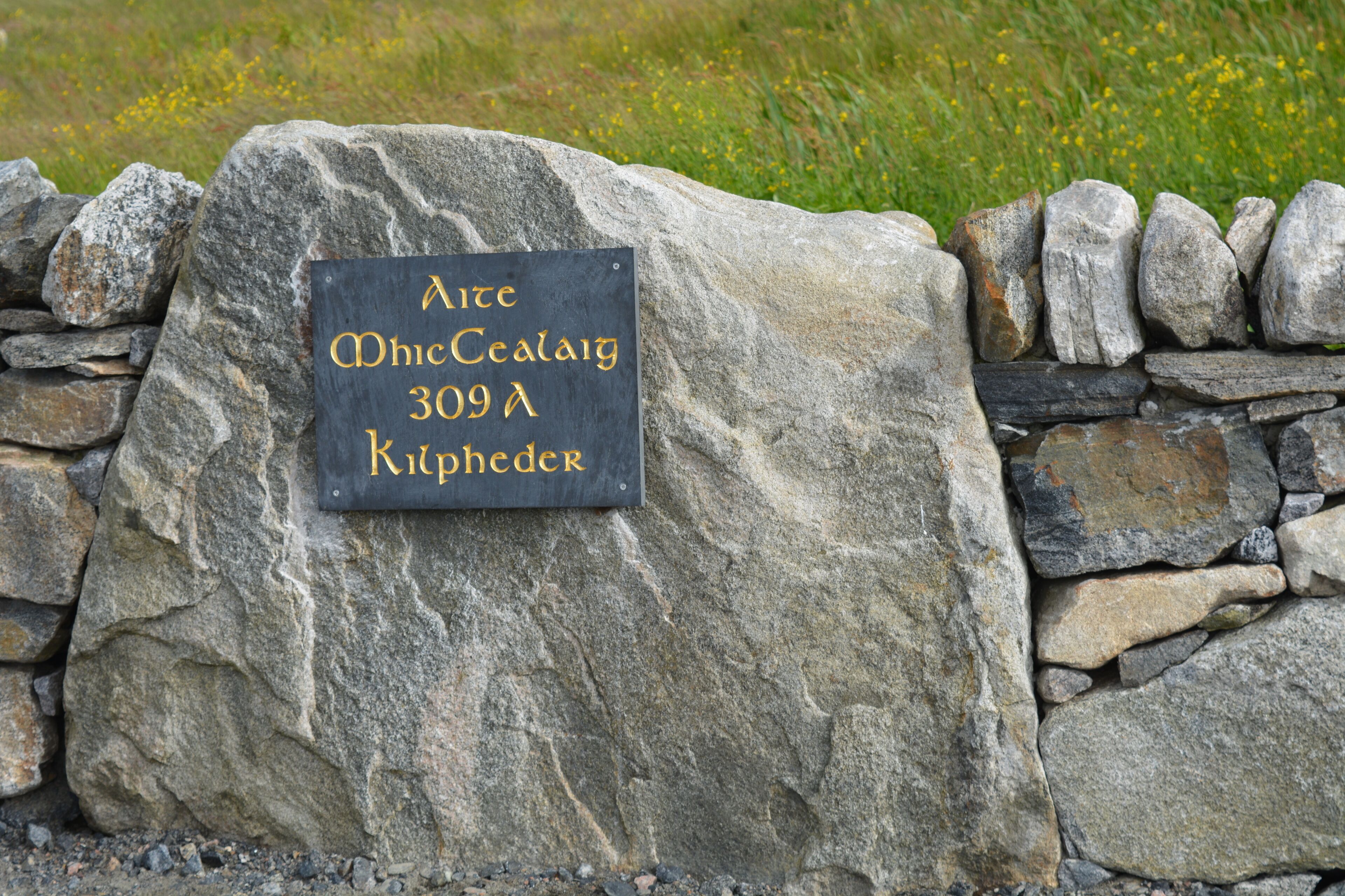 A stone wall with a sign that reads "Ard Mhacha 309 A Kilphedder."