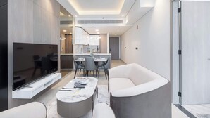 A modern living room with a flat-screen TV, a round coffee table, and two armchairs. - StayShort - Comfortable 1BR Apartment in JVT with Gym & Pool Sleeps 2 (JVT)
