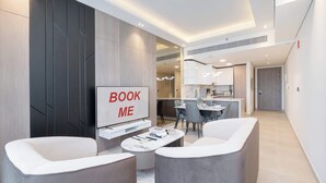 A modern living room with a TV, two sofas, a coffee table, and a 'BOOK ME' sign. - StayShort - Comfortable 1BR Apartment in JVT with Gym & Pool Sleeps 2 (JVT)