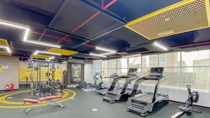 A gym with treadmills, weight machines, and a red bench.