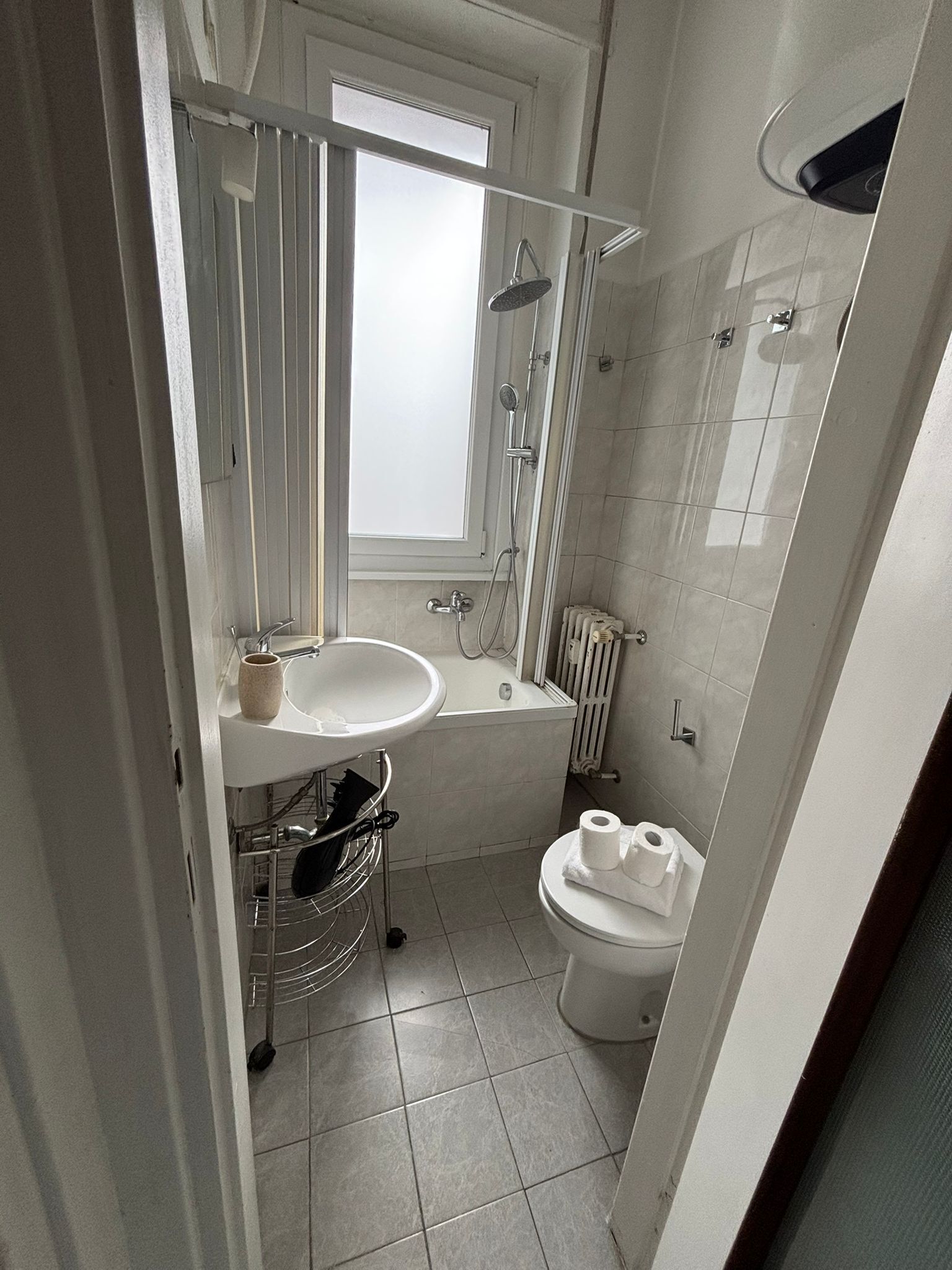 A modern bathroom with a sink, mirror, window, shower, and toilet.