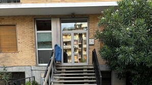 A building entrance with a set of concrete steps leading up to a glass door, a small tree to the right, and a metal railing on the left. - Cosy Studio Quick Metro Ride to Centre (Milan)