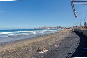 Una spiaggia con persone che prendono il sole e passeggiano lungo la riva.