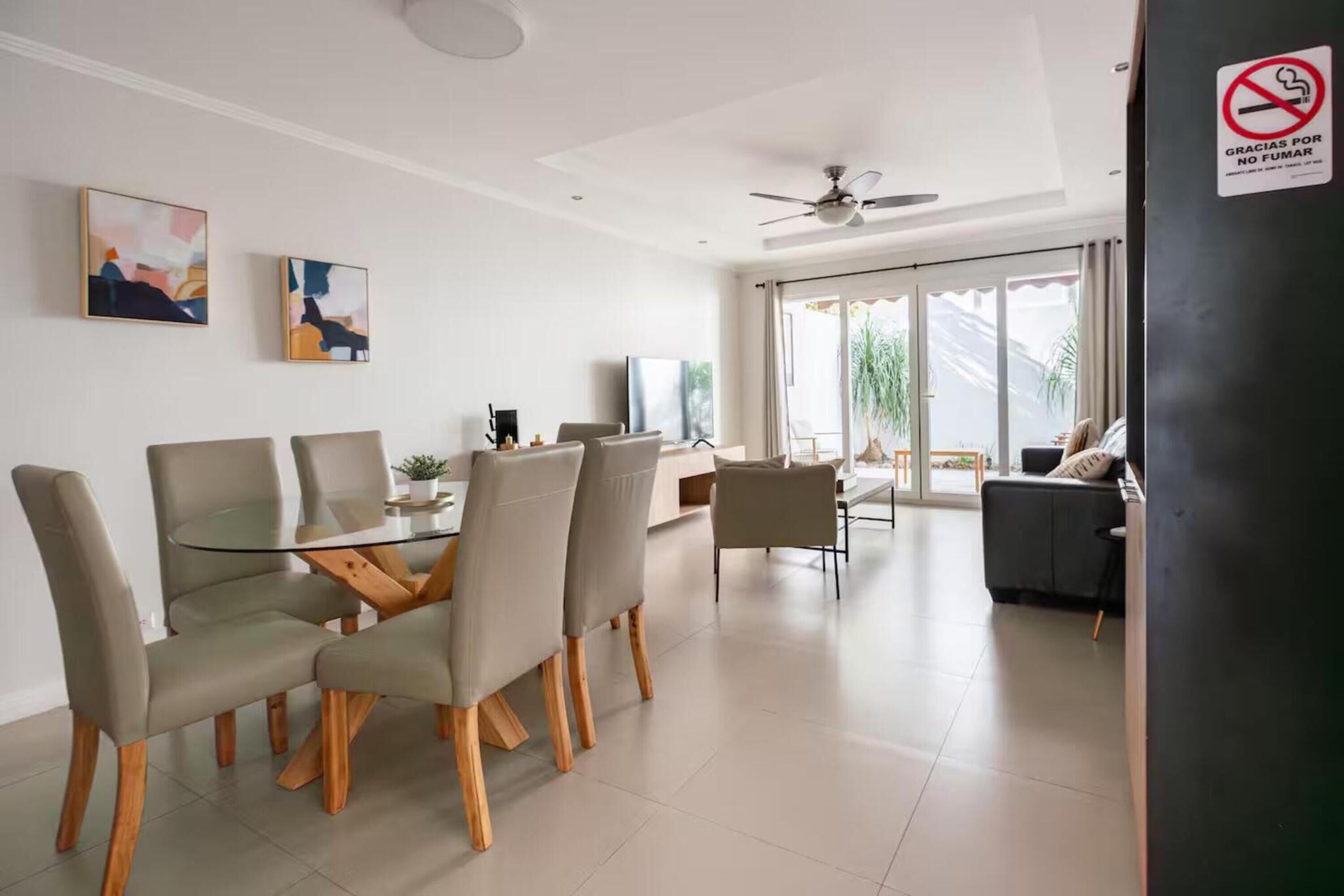 Una sala moderna con comedor, ventilador de techo y vistas al exterior.
