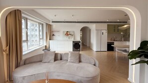 A modern apartment with a curved sofa, a dining area, and a kitchen.