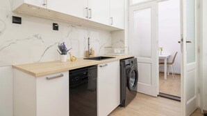 Una cocina moderna con lavavajillas, lavadora y un lavamanos pequeño.