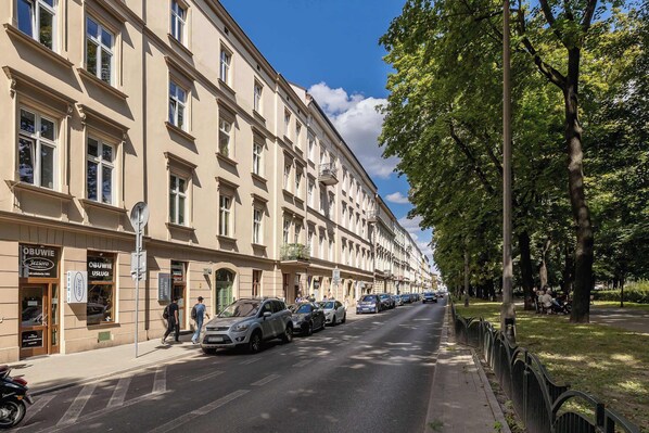 A street with parked cars and a building with multiple windows and balconies.
