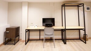 A compact room with a wooden desk, a black monitor, a white chair, and a small cabinet. - Little Rooms (Chanthaburi)