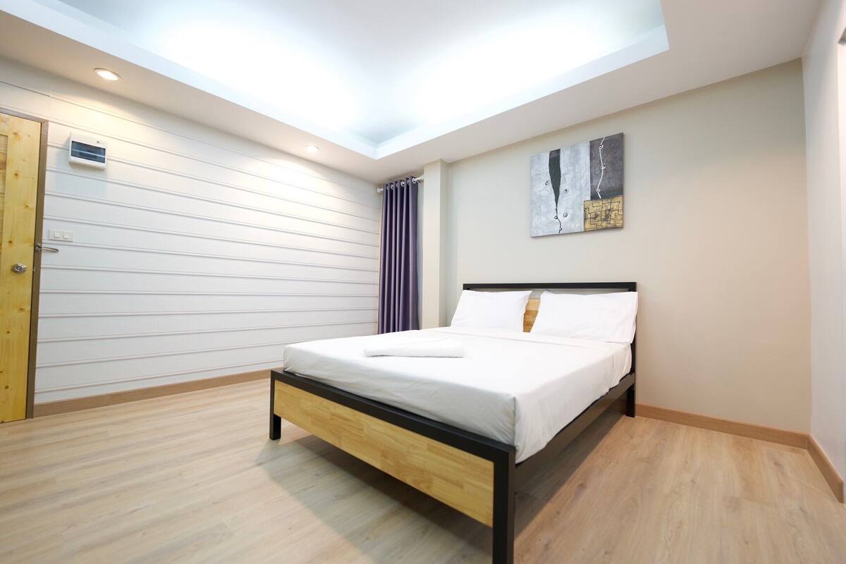 Ein modernes Schlafzimmer mit Dachfenster, einem Bett mit weißer Bettwäsche, Holzboden und einem Bild an der Wand.