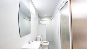 A modern bathroom with a sink, mirror, toilet, and shower area. - Little Rooms (Chanthaburi)