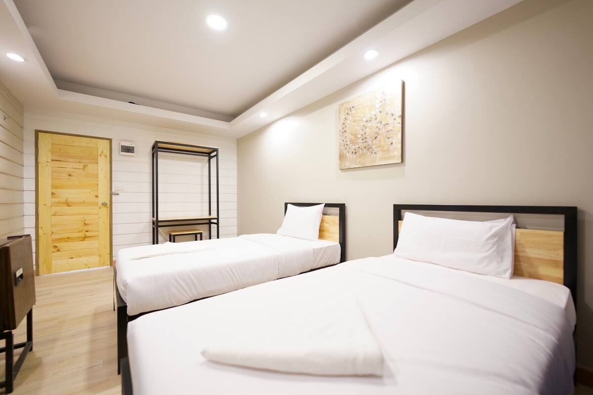 Ein Hotelzimmer mit zwei Betten, einer Holztür und einem an der Wand befestigten Kunstwerk.