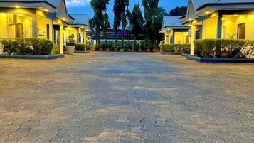 A hotel with a paved courtyard, two-story buildings, and a central entrance with trees.