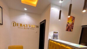 Ein Empfangsbereich mit einem gelben Polstersessel, einem Empfangstresen mit einer gesteppten Rückenlehne und einem Wandzeichen, das 'Debayview Hotel' zeigt.