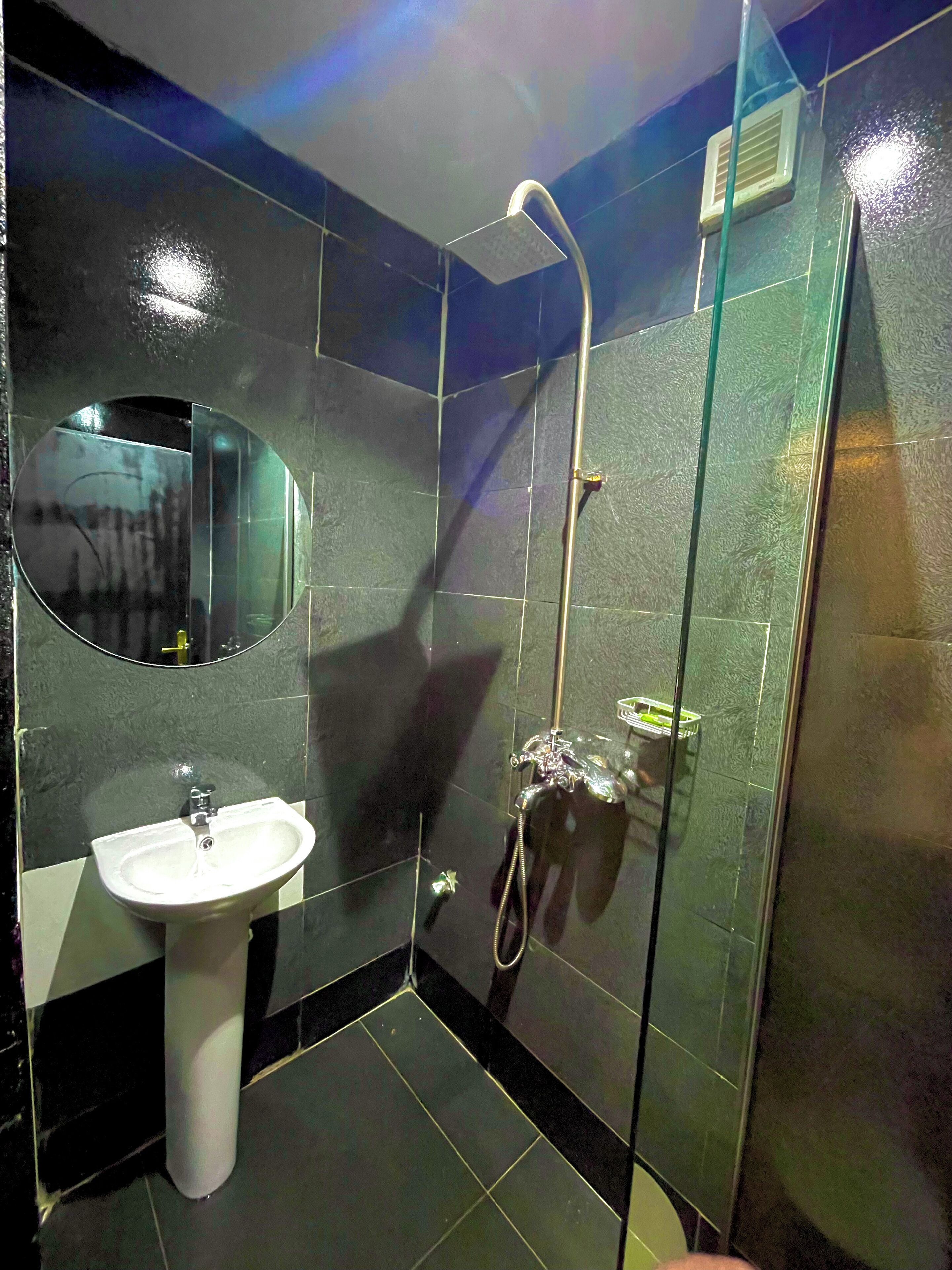A bathroom with a white sink, a mirror, and a glass-enclosed shower area.