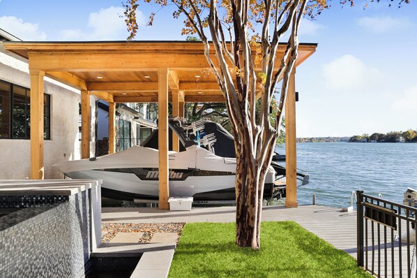 A modern boat house with a covered deck, a tree, and a dock extending into a lake. - Above Austin Diamond on Lake Austin (Austin)