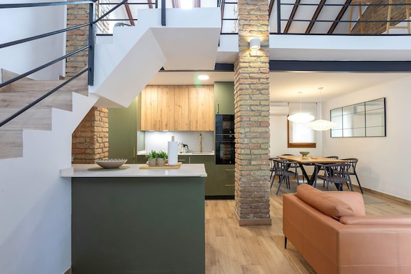 A modern interior with a staircase, kitchen, dining area, and a sofa.