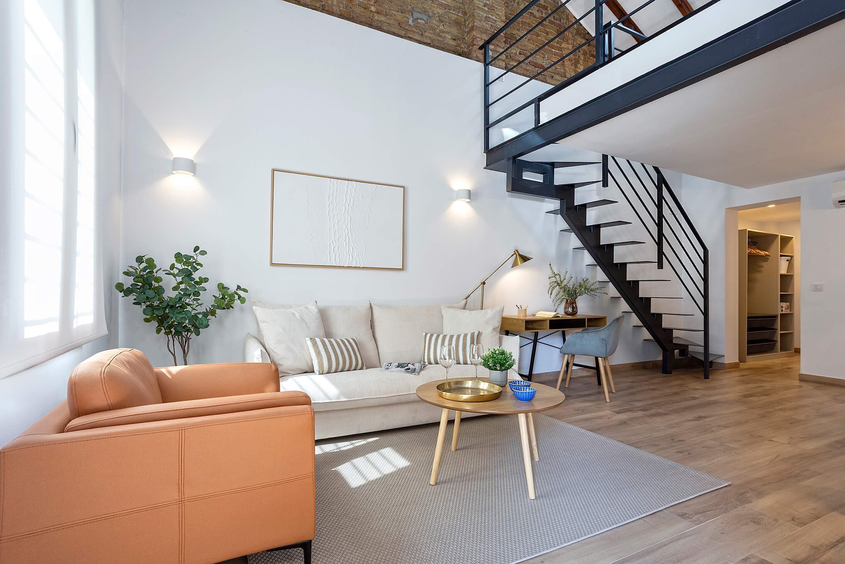 Una sala de estar moderna con un sofá, una mesa de centro y una escalera.