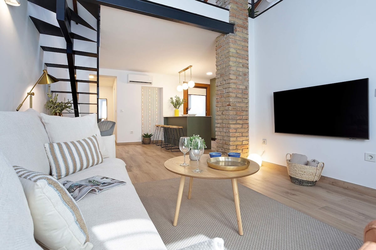 Ein modernes Wohnzimmer mit einer Couch, einem runden Couchtisch und einem an der Wand befestigten Fernseher.