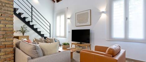 A modern living room with a sofa, armchair, and a flat-screen TV.