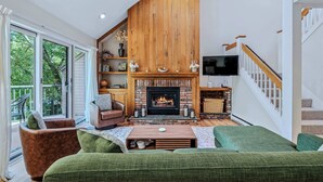 A spacious living room with a fireplace, green sofas, a wooden ceiling, and a staircase. - Condo with Fireplace & Pool, Deere Run (Quechee)