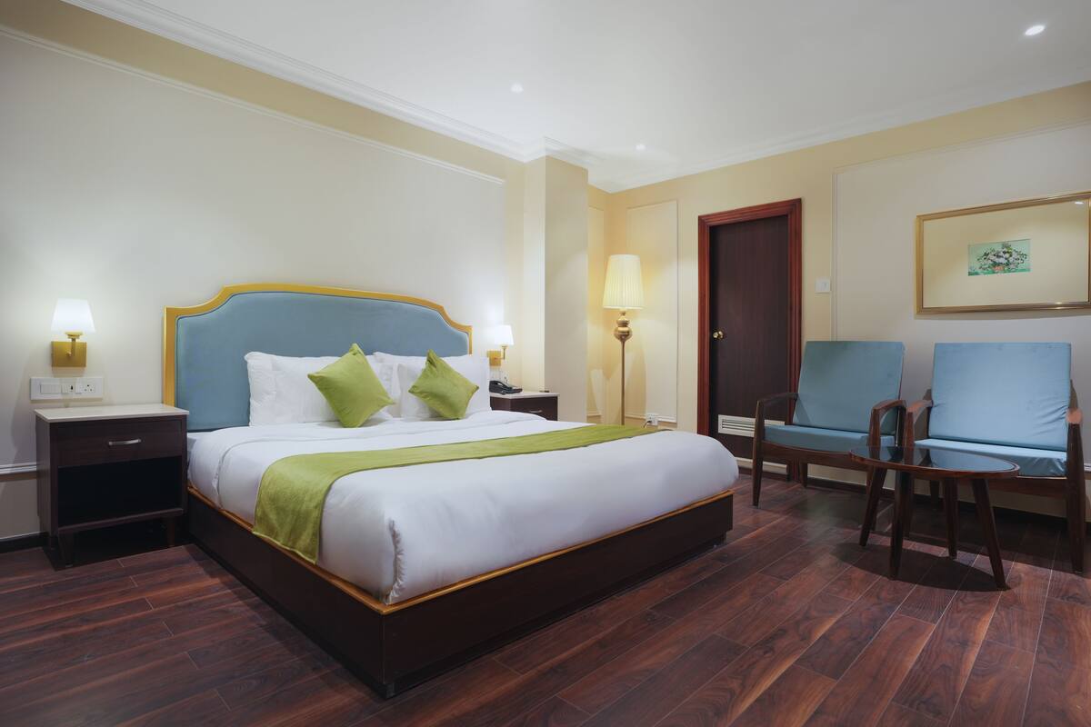 Une chambre d’hôtel avec un grand lit, deux tables de chevet, une chaise et une porte.