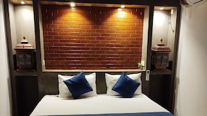 A bed with a white and blue bedspread, two blue pillows, and a wooden headboard with a brick pattern.