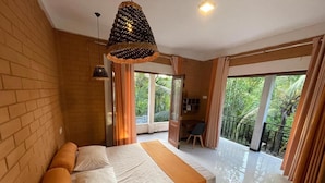 A modern bedroom with a large bed, a balcony with curtains, and a view of greenery outside.