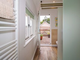 A narrow hallway with a radiator, a window, and a door leading to a garden.