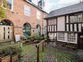 A courtyard with a cobblestone path, a wooden bench, and potted plants.
