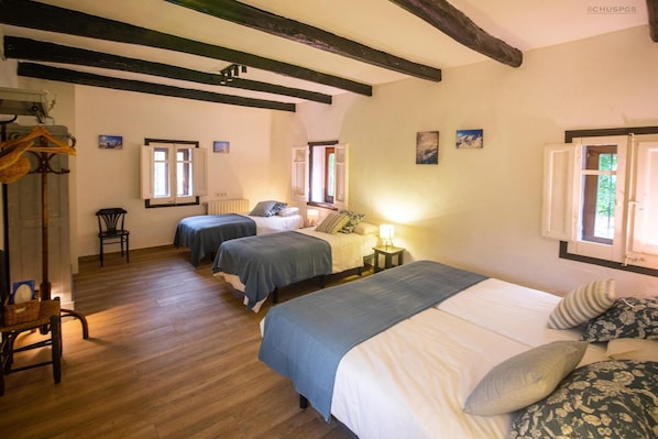 Ein Zimmer mit zwei Betten, Holzböden und einem Stuhl.