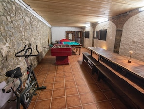 Ein Zimmer mit Fußballtisch, einer Bank, einem Fahrrad und einem Wandregal.