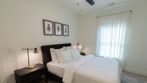 A neatly arranged bedroom with a bed, a bedside table, and a nightstand. There are three framed pictures on the wall above the bed. - Upscale Lodge Sleeps 9 Dog Friendly Near CU (Central)