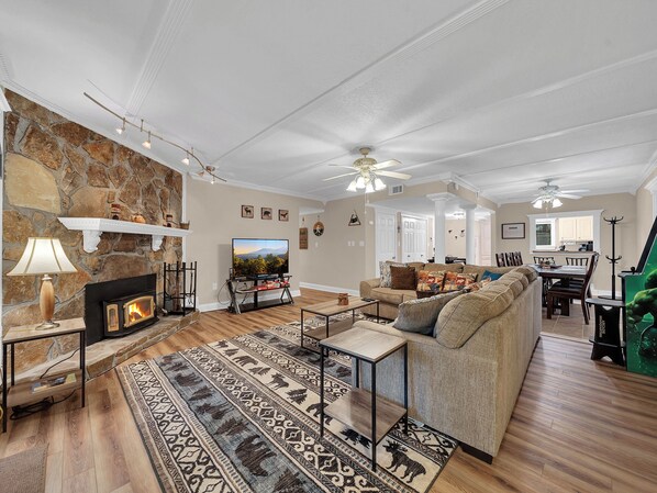 A spacious living room with a stone fireplace, a television, and a large sofa.