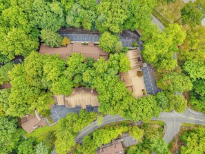An aerial view of a residential area with a parking lot, a road, and a building with a sloped roof.