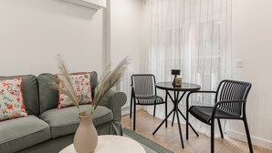 A modern living room with a grey sofa, two black chairs, a small round table, and a vase with pampas grass. - Waou Malasaña VII - Short Term Rental (Madrid)