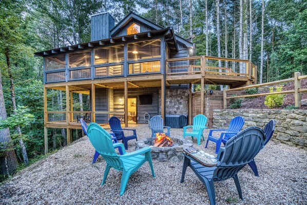 Uma cabana com lareira de pedra, área de estar externa e um deck.