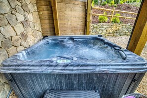 Uma banheira de hidromassagem com parede de pedra e deck de madeira.
