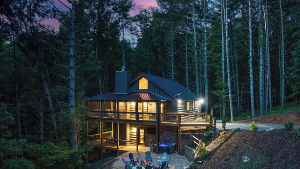 Une cabane à deux étages avec une terrasse, entourée d’une forêt.
