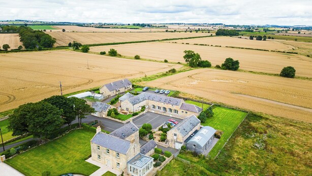 A large stone building with multiple wings, surrounded by expansive fields and a few trees. - 
A beautifully restored cottage, sitting on the stunning Northumbrian coastline. (Warkworth)