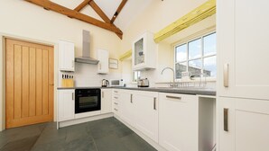 A modern kitchen with white cabinets, a wooden door, and a large window. - 
A beautifully restored cottage, sitting on the stunning Northumbrian coastline. (Warkworth)