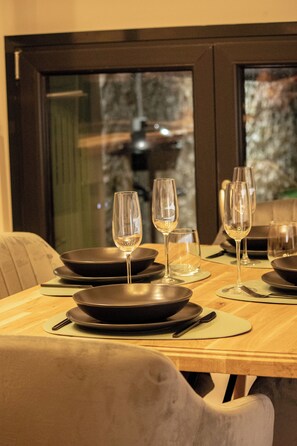Una mesa de comedor dispuesta con platos negros, copas de vino y cubiertos.