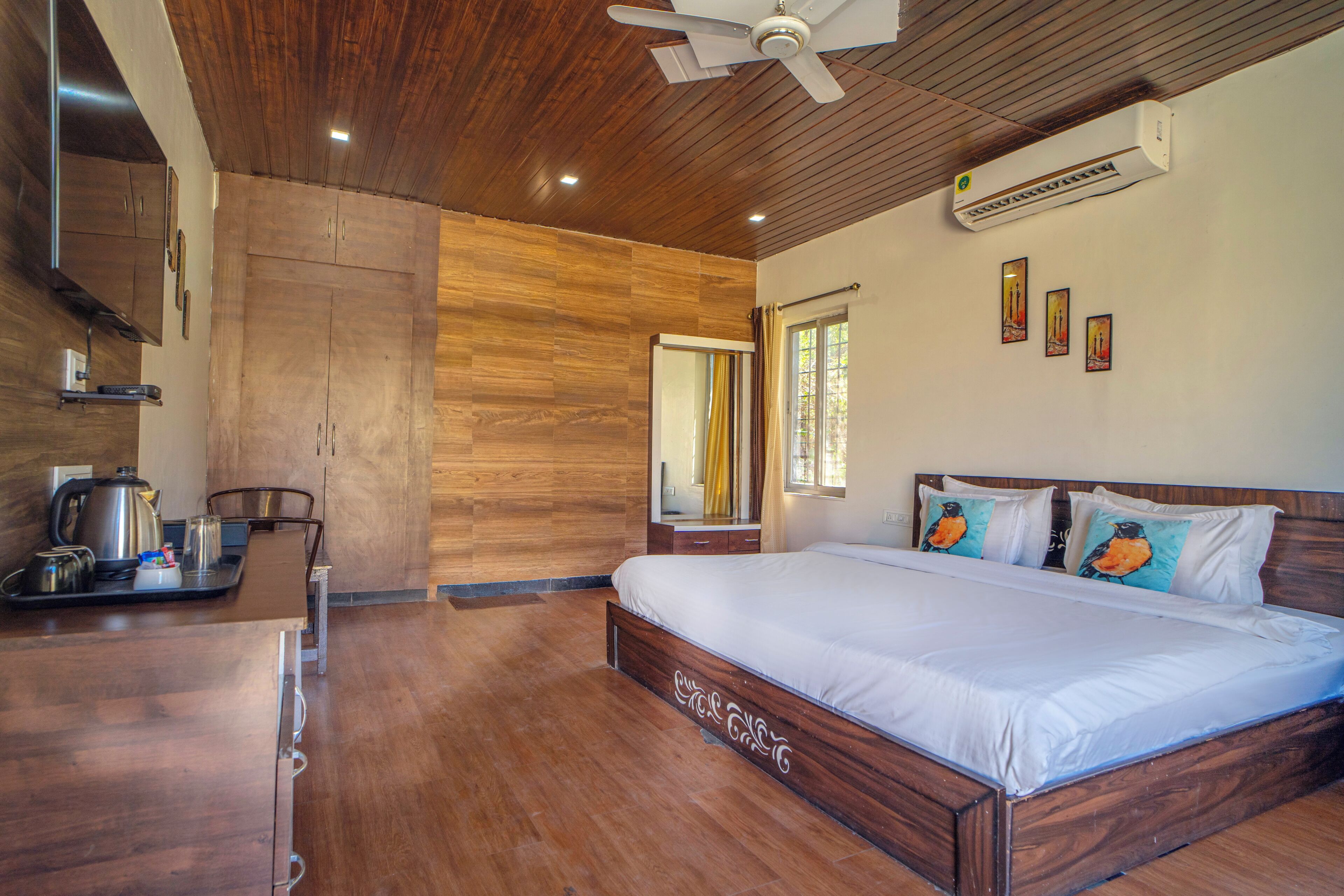 A bedroom with a wooden ceiling, a bed with white bedding, a ceiling fan, and an air conditioning unit.